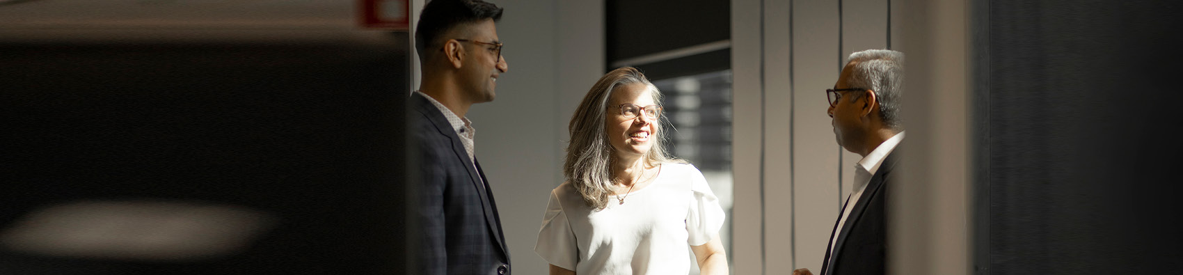 Three workers standing in an office and talking.