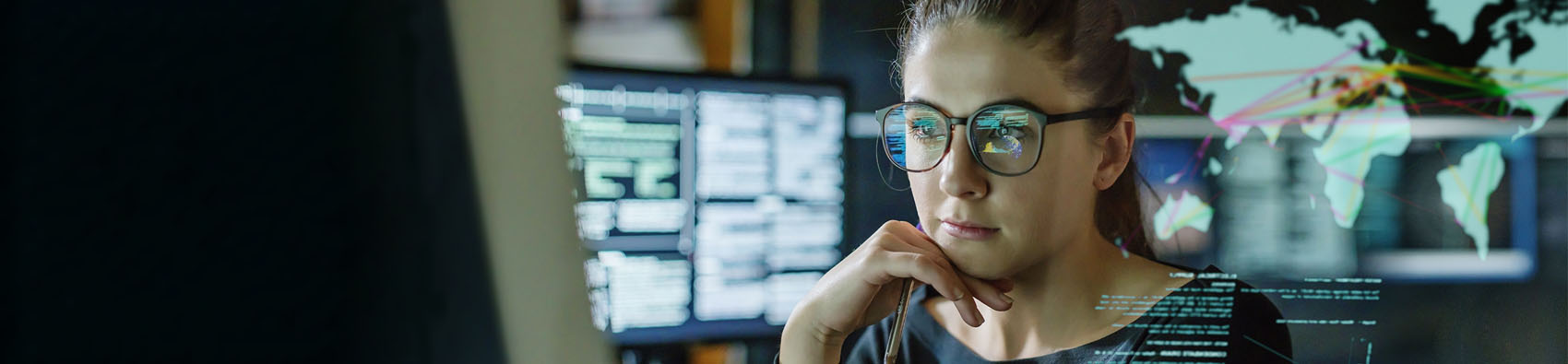 A person in an office looking at a monitor. The person is surrounded by screens.