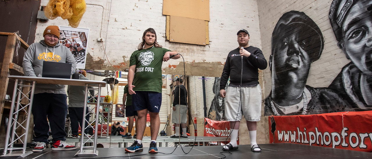 Three teenagers who are participants in the Hiphopportunities for Youth hiphop music program standing in the studio with musical instruments. 