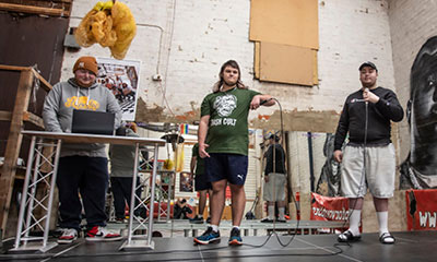 Three teenagers who are participants in the Hiphopportunities for Youth hiphop music program standing in the studio with musical instruments. 
