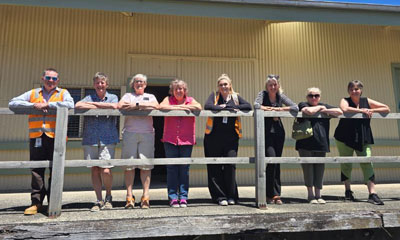 A group of 8 people standing in front of the Korumburra Goods shed.